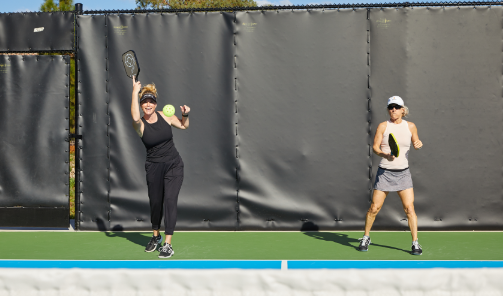 Two women playing pickle ball outdoors