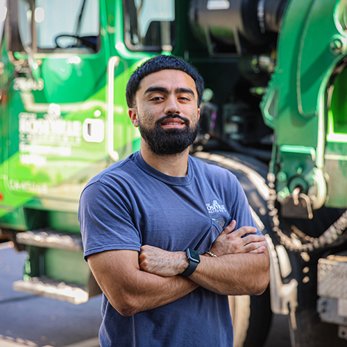 A truck driver stands outside in front of his truck