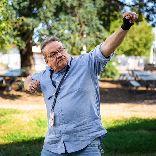A man stands in a park punching the sky