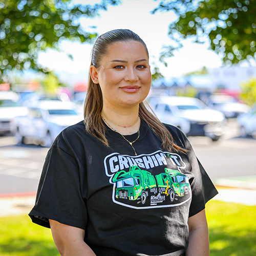 A woman stands outside with her department shirt
