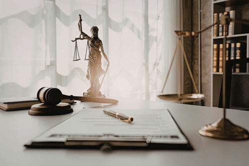 Desk with legal documents, pen, gavel, and Lady Justice statue