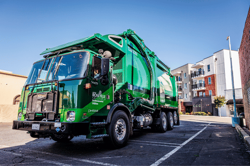 Garbage truck with apartment complex in the back