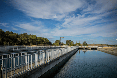 Water treatment facility with concrete basins and railings under a blue sky