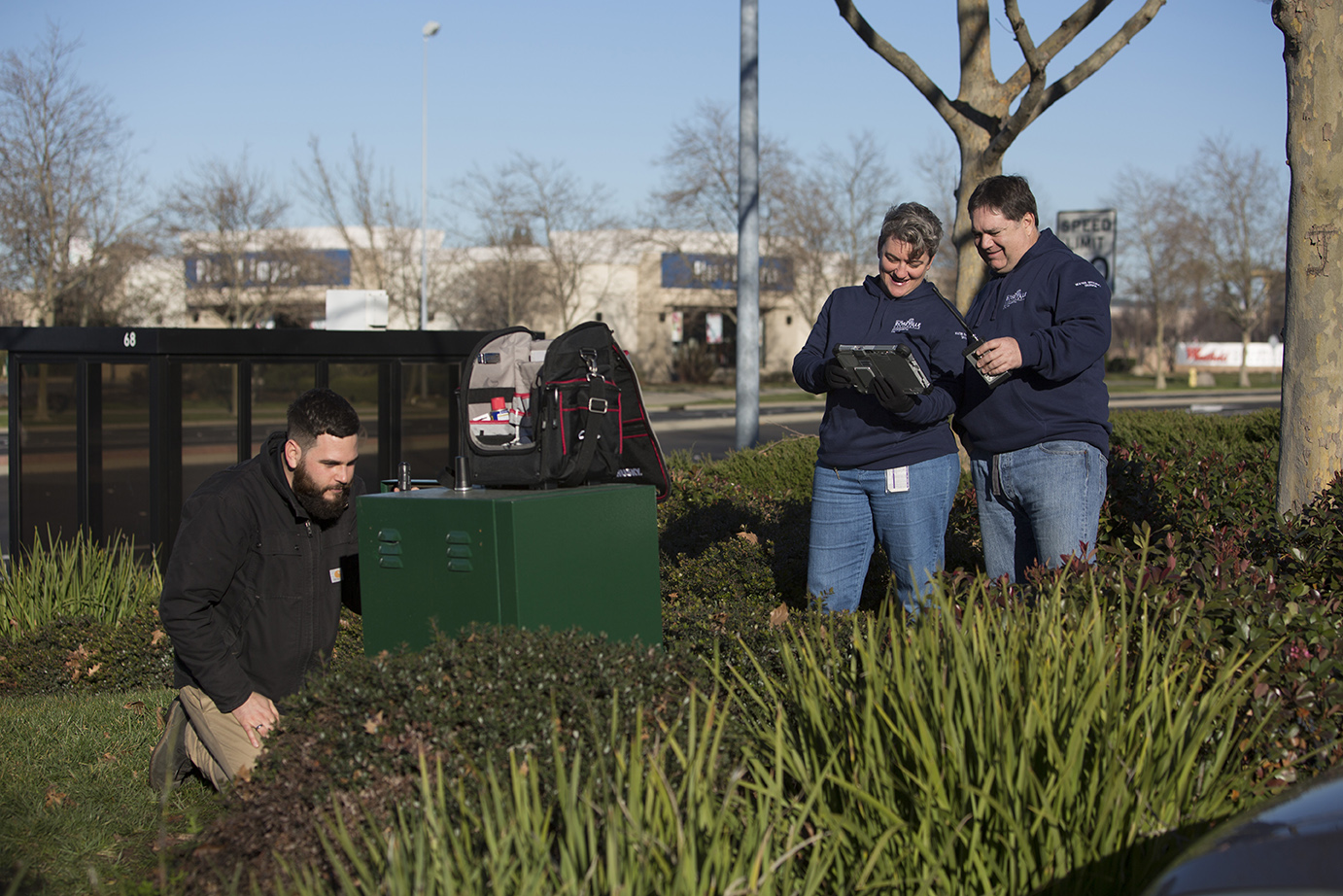 Three individuals in a retail center reviewing landscaping