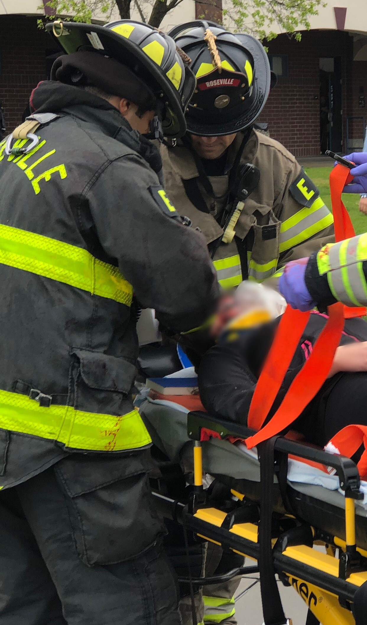 three firefighters treat a patient who is strapped to a gurney during a training exercise