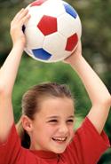 Girl holding a soccer ball above her head.
