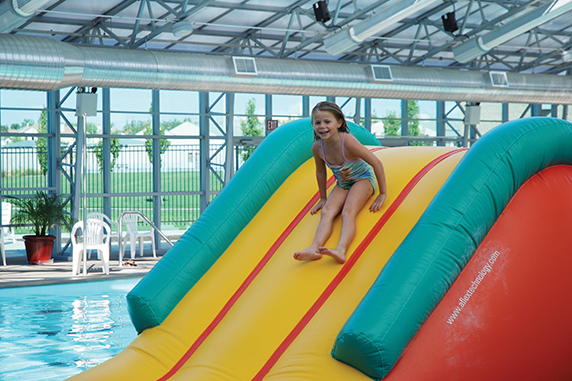 Girl on inflatable pool slide at Mike Shellito Indoor Pool