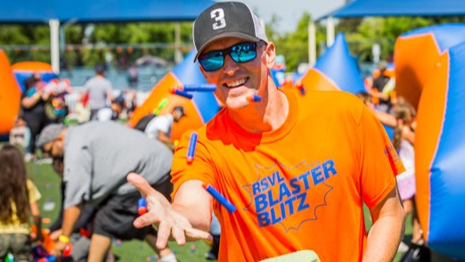 Male in bright shirt throwing foam darts in the air