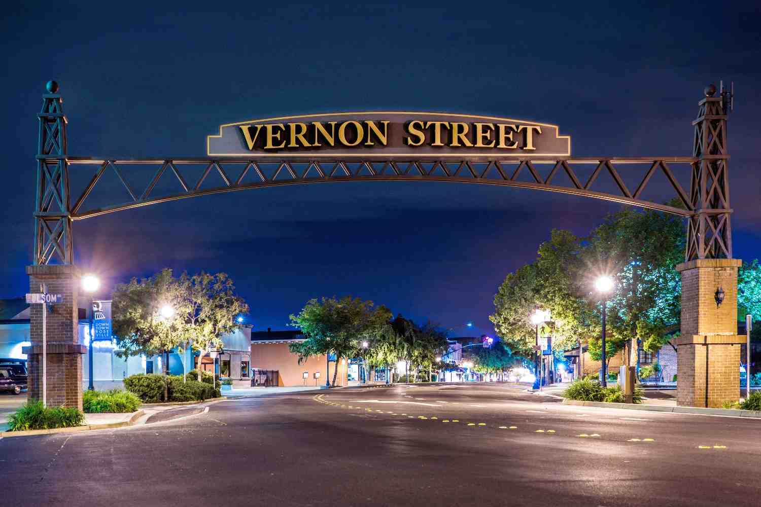 Vernon Street sign spans over Vernon Street as streetlights illuminate it from behind.