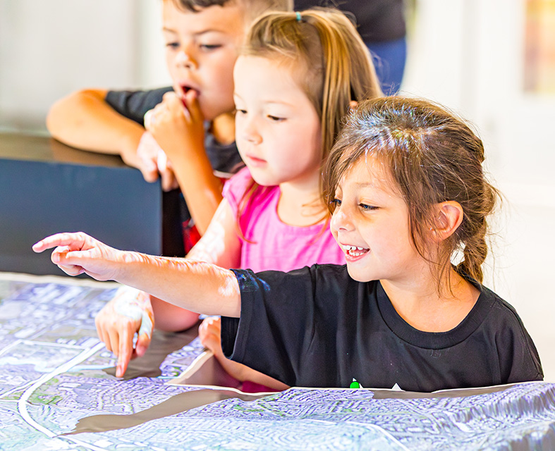 Elementary school kids pointing at a map