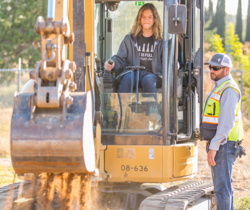 Highschool boy in tractor with utility worker standing by