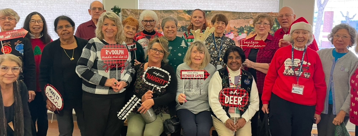 Group of 18 older adults in festive holiday attire smiling 
